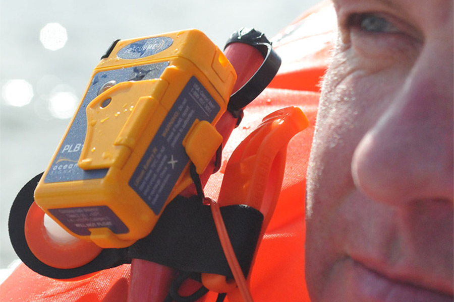 Close up of the Ocean Signal RescueMe PLB1 attached to a life vest. The side of a man's face takes up the right of frame.