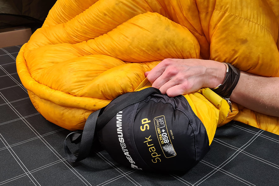 A Spark SP4 sleeping bag turned inside out and being stuffed into its compression sack.