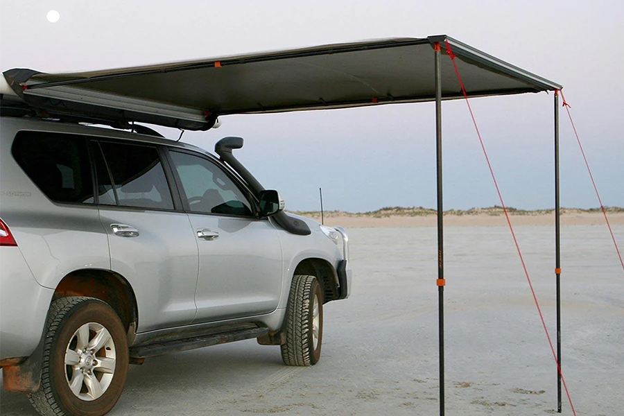 A 4WD with an awning extended, on the beach.